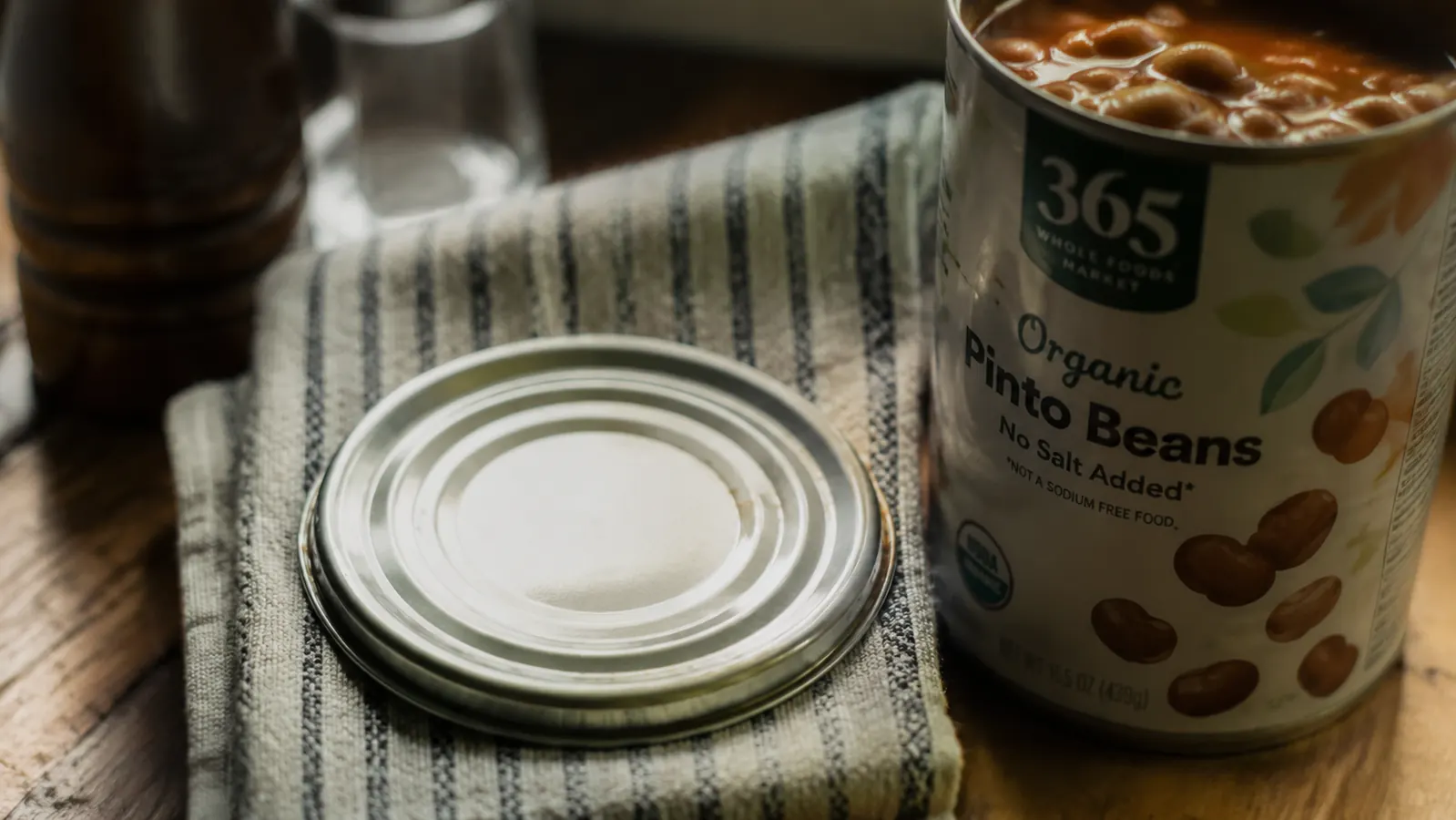 Close-up of a smooth, safe-edge lid sitting beside an open can after being removed by an electric opener