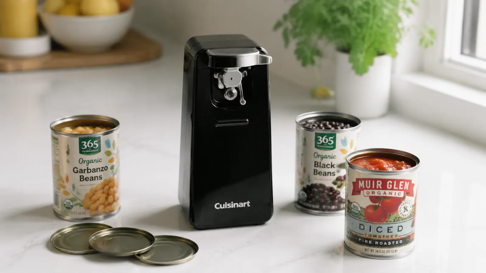 Cuisinart electric can opener on a clean white kitchen counter next to several opened cans of beans and tomatoes