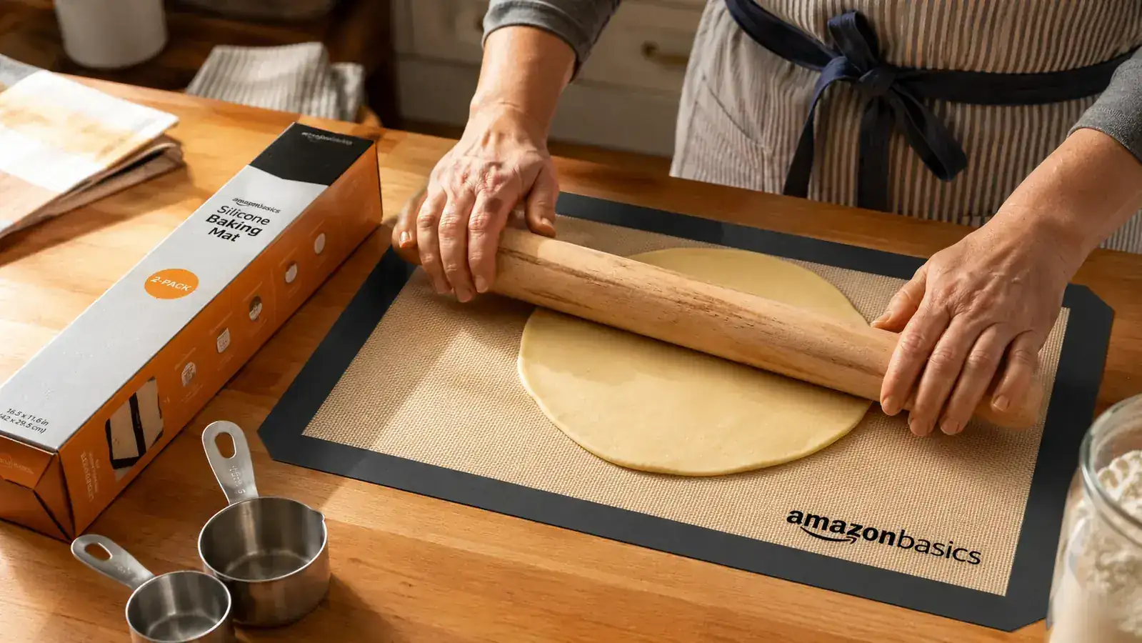 Amazon Basics silicone baking mat laid flat on a light countertop next to a rolling pin and measuring cups