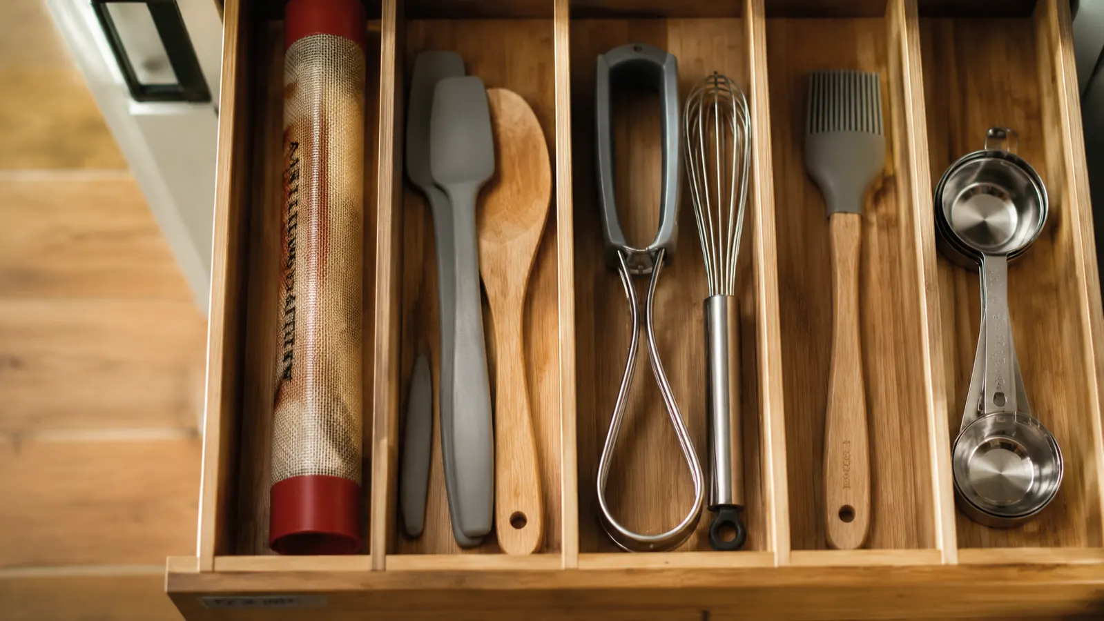 Rolled silicone baking mat stored upright in a kitchen drawer organizer next to spatulas and flat baking tools